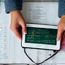 Manos de médico y paciente en una mesa, con gráficos de salud y una lupa, simbolizando monitoreo proactivo.